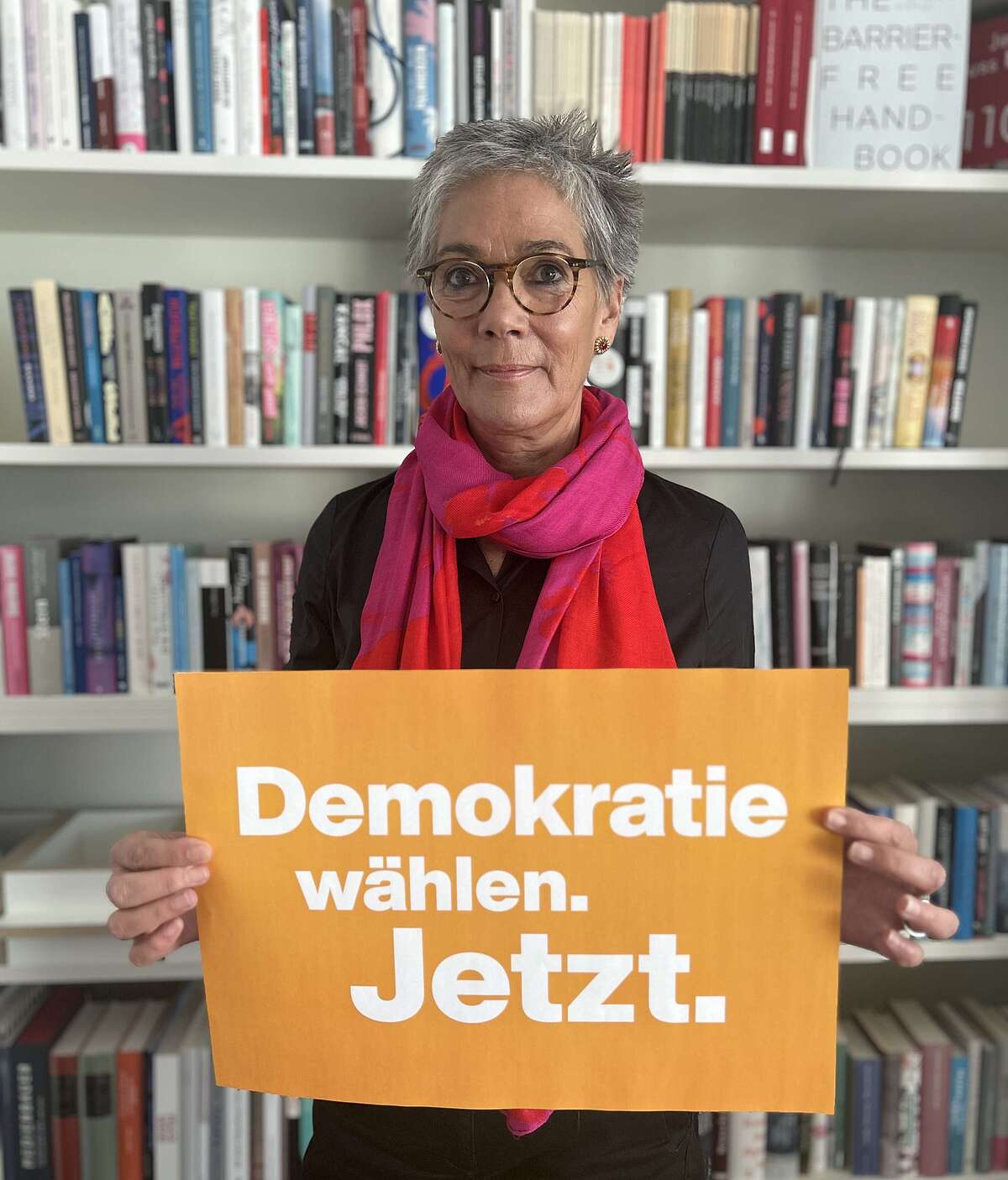 Vorsteherin Karin Schmidt-Friderichs hält ein Plakat in der Hand mit dem Schriftzug "Demokratie wählen. Jetzt."