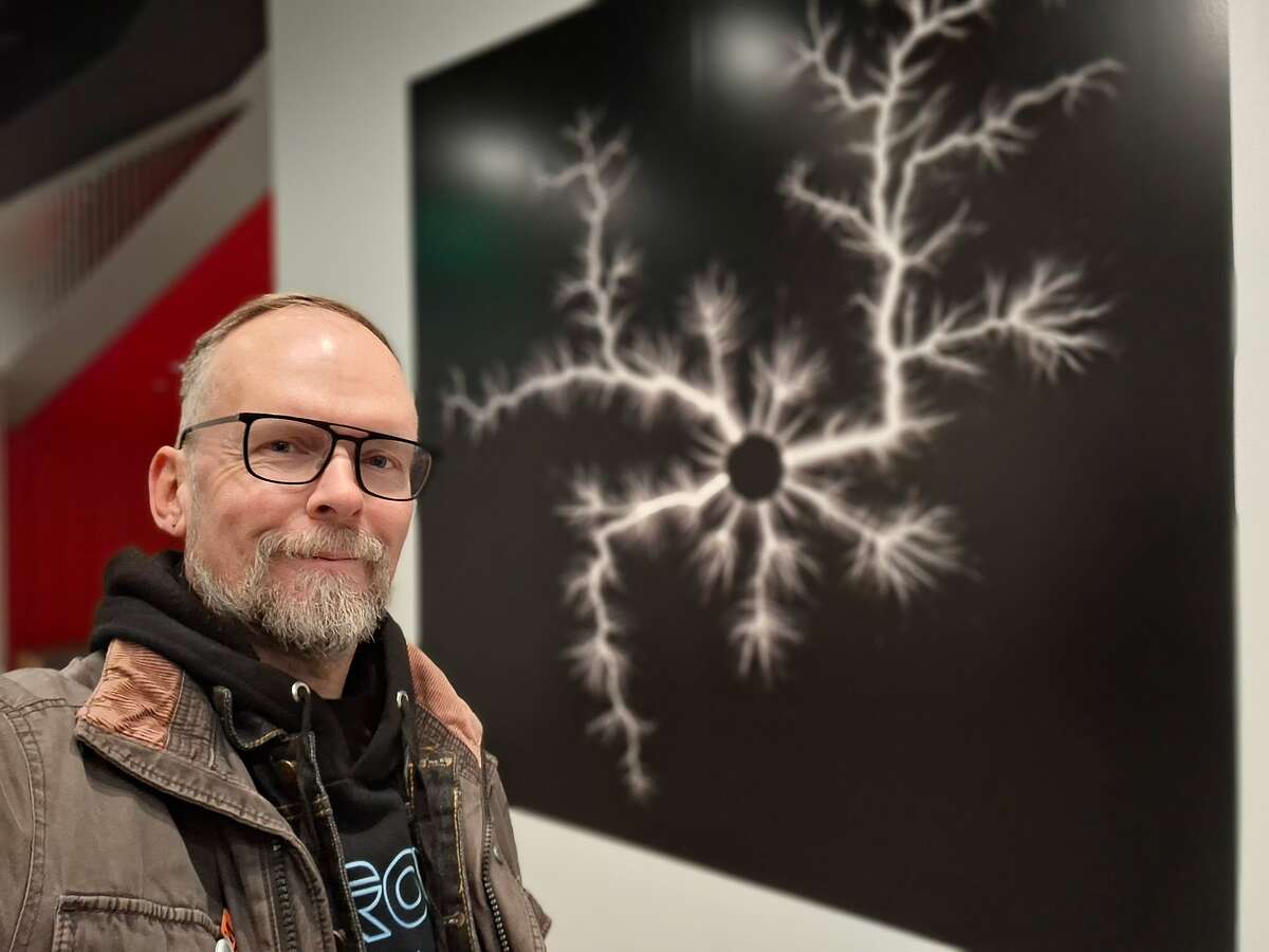 Porträtfoto Dietmar Dath vor einer schwarzen Tafel mit weißer Grafik